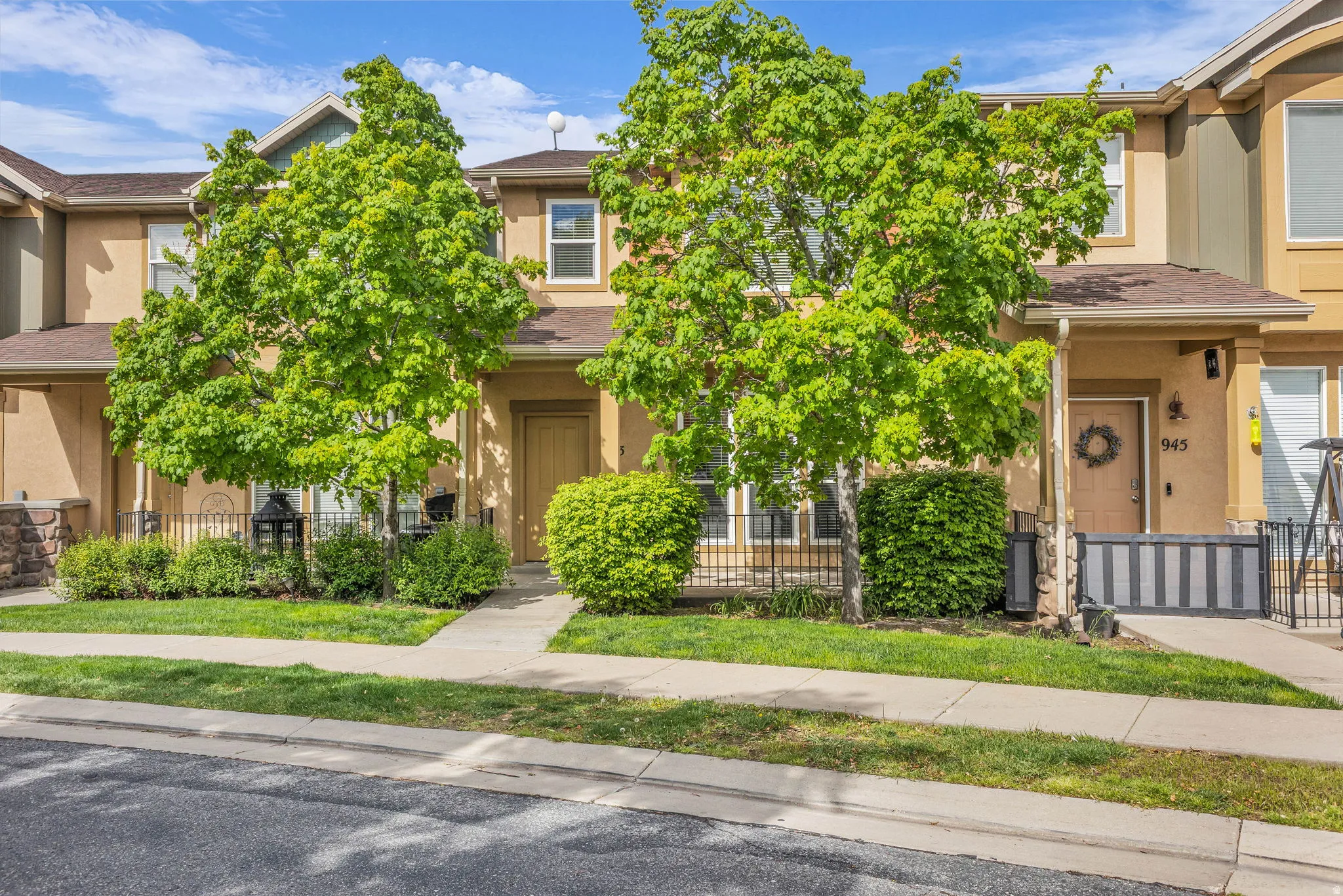 View of property hidden behind natural elements with a fenced front yard, stucco siding, and a gate