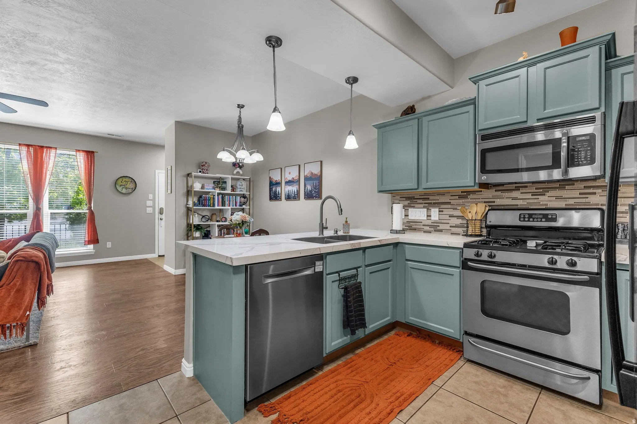 Kitchen featuring a chandelier, stainless steel appliances, light tile patterned floors, a peninsula, and open floor plan