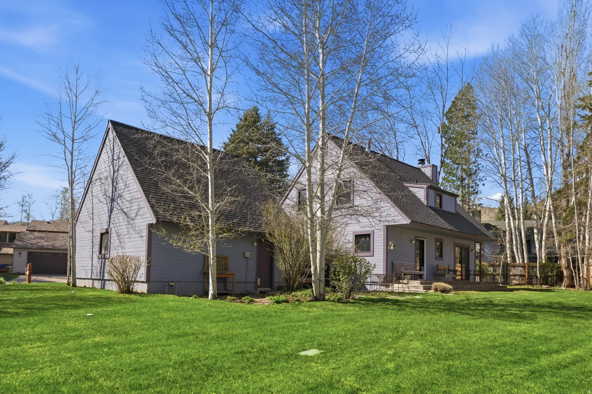 View of side of property featuring a lawn, a shingled roof, a chimney, and a patio area