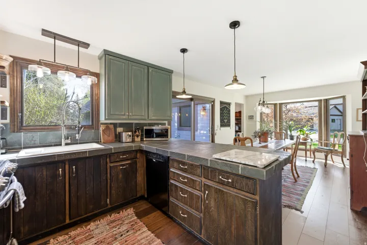 Kitchen featuring a peninsula, dark wood finished floors, pendant lighting, and tile counters