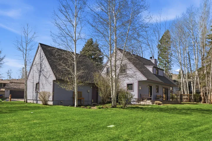 View of side of property featuring a lawn, a shingled roof, a chimney, and a patio area