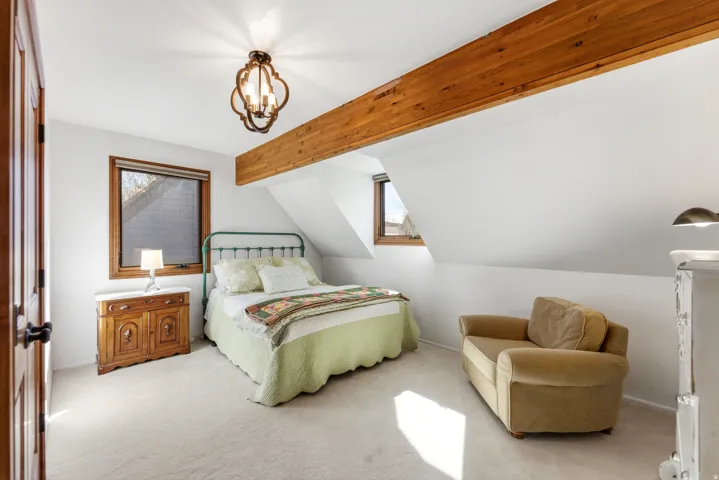 Bedroom featuring carpet floors, multiple windows, beamed ceiling, and suspended lighting