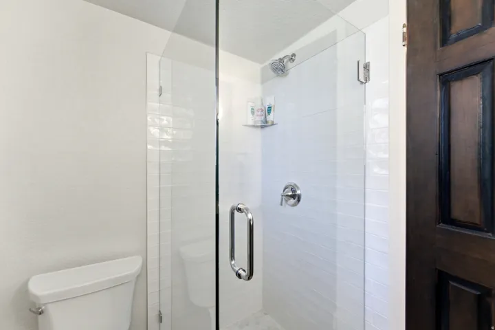 Bathroom with a stall shower, a textured ceiling, and a textured wall