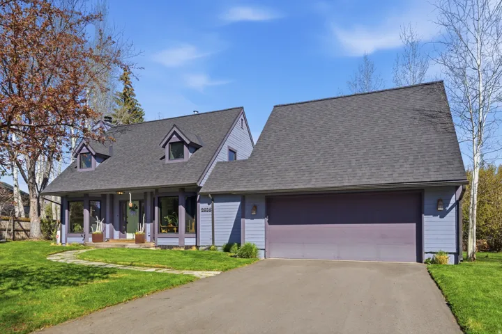 New england style home with a front lawn, a porch, a garage, and driveway