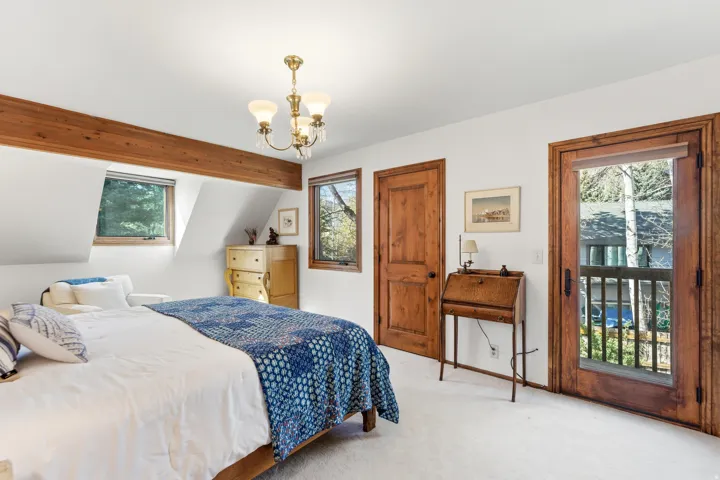 Carpeted bedroom with a chandelier and multiple windows