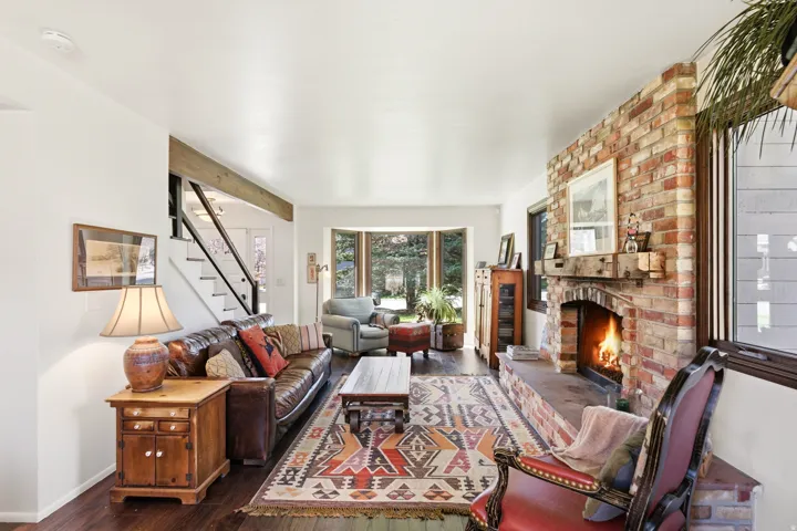 Living room featuring dark wood-style flooring and a brick fireplace