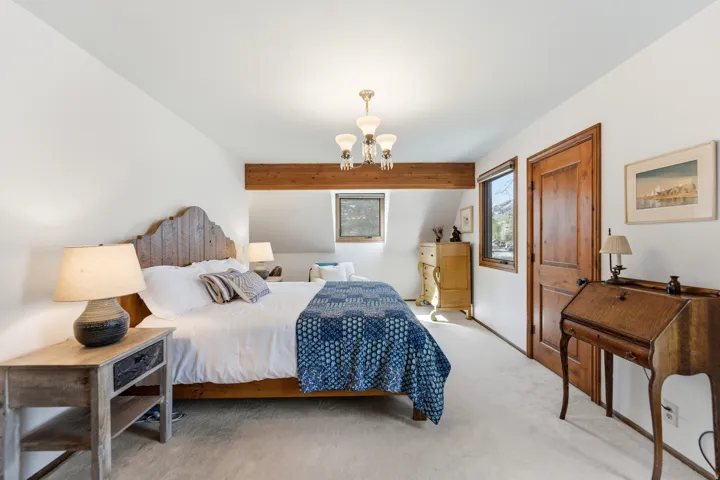 Bedroom with light colored carpet and a chandelier