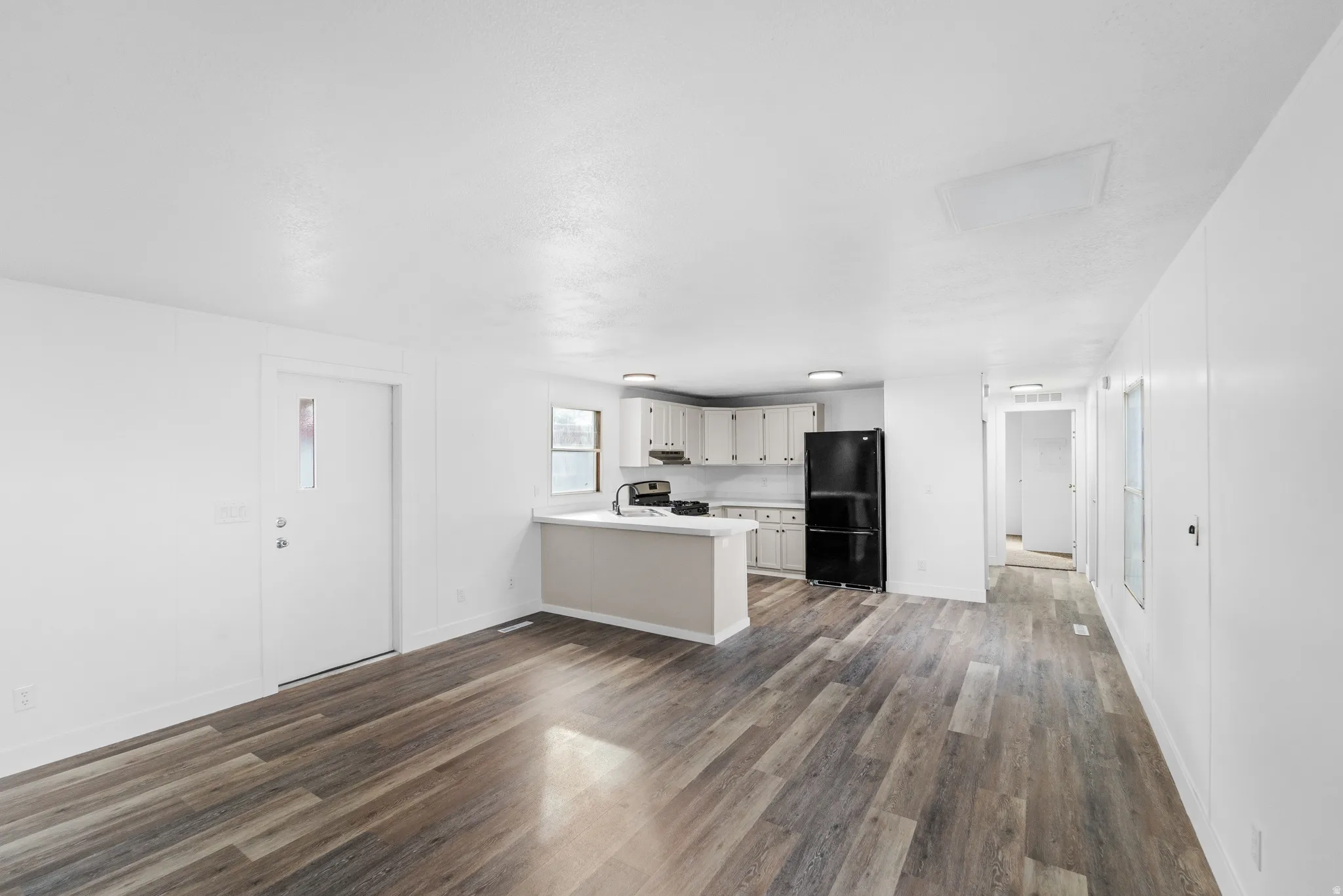 Unfurnished living room featuring dark wood-type flooring and baseboards