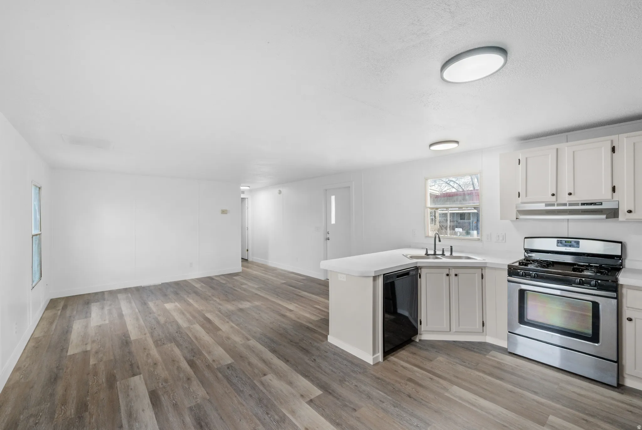 Kitchen with a peninsula, gas range, light countertops, and open floor plan