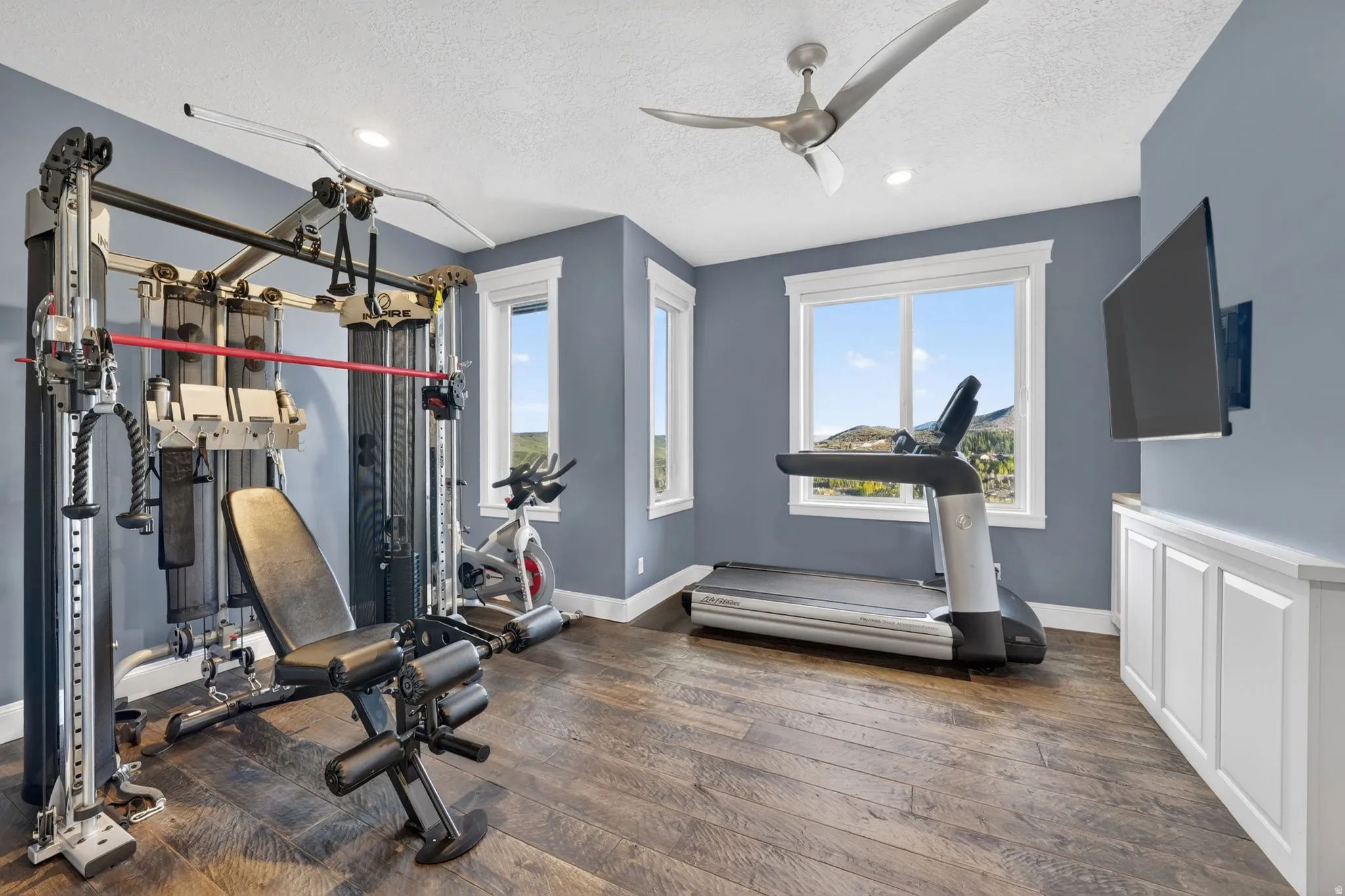 Workout area featuring a ceiling fan, a textured ceiling, and recessed lighting