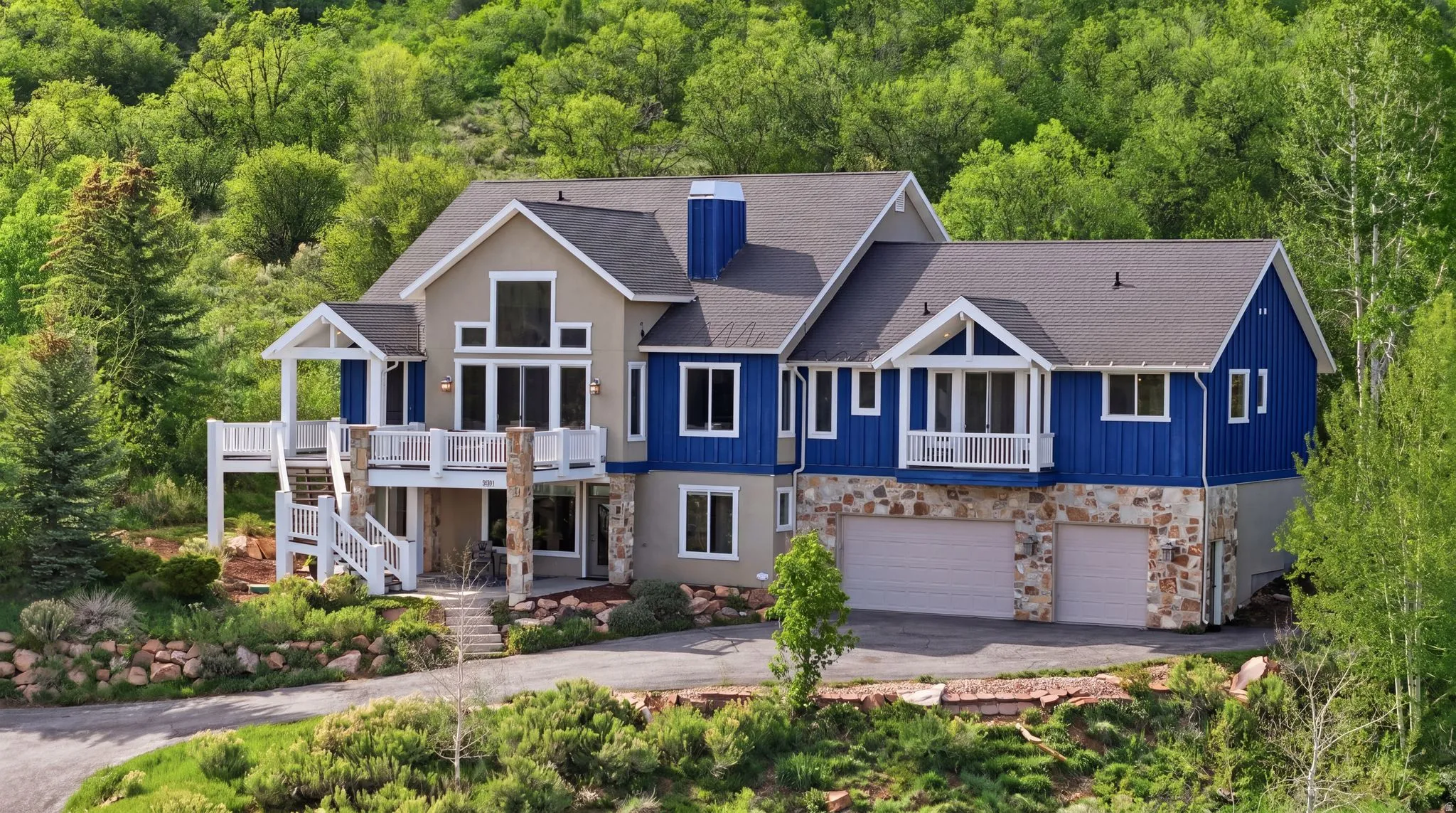 View of front of house featuring an attached garage, a shingled roof, stone siding, and asphalt driveway