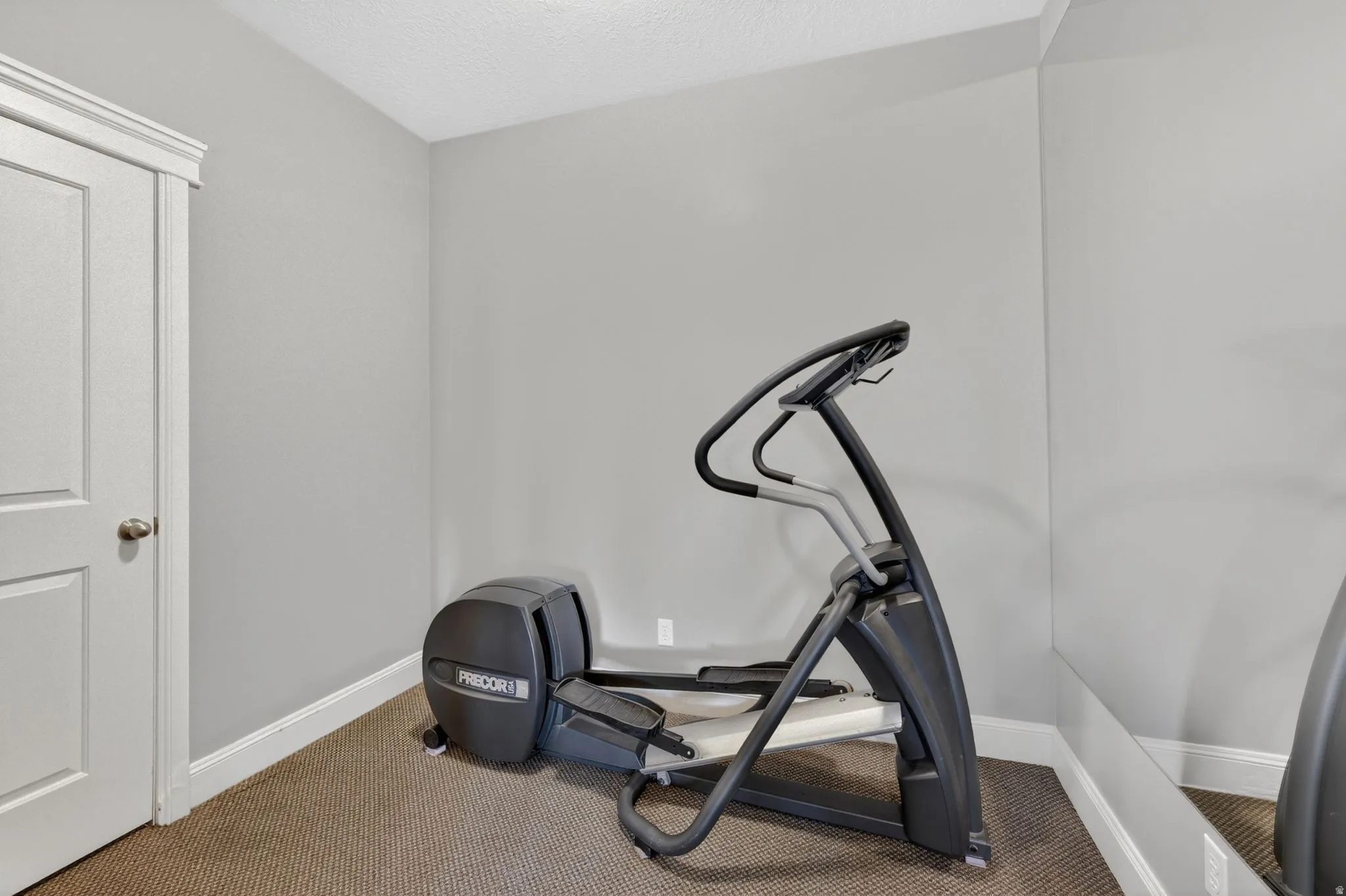 Workout area with carpet flooring and a textured ceiling