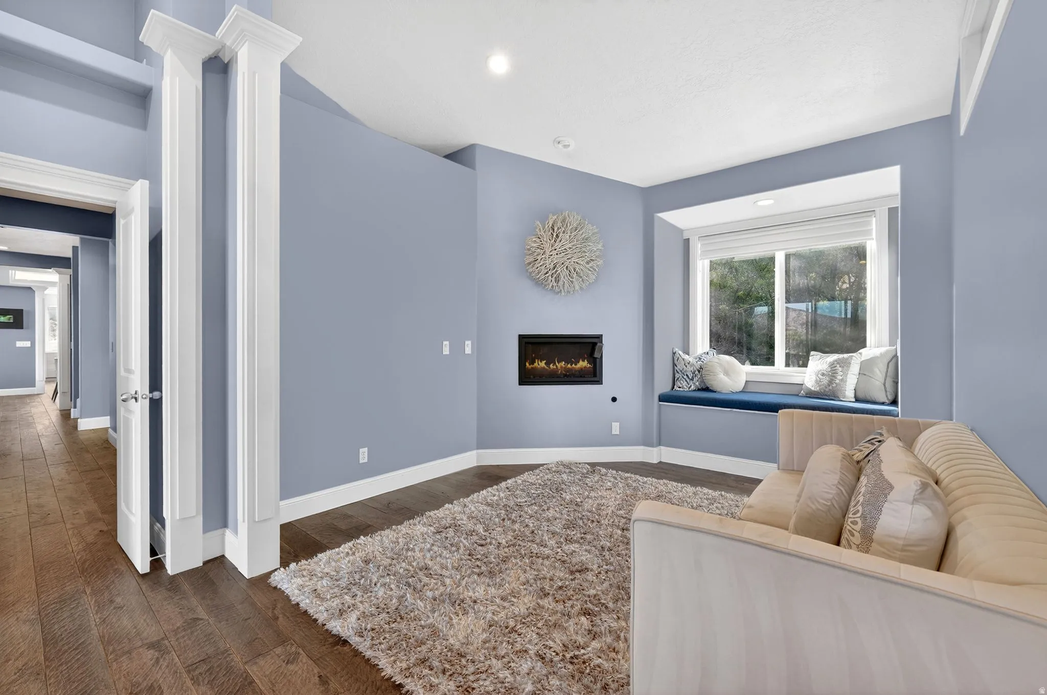 Living area featuring dark wood-style flooring, a glass covered fireplace, and recessed lighting