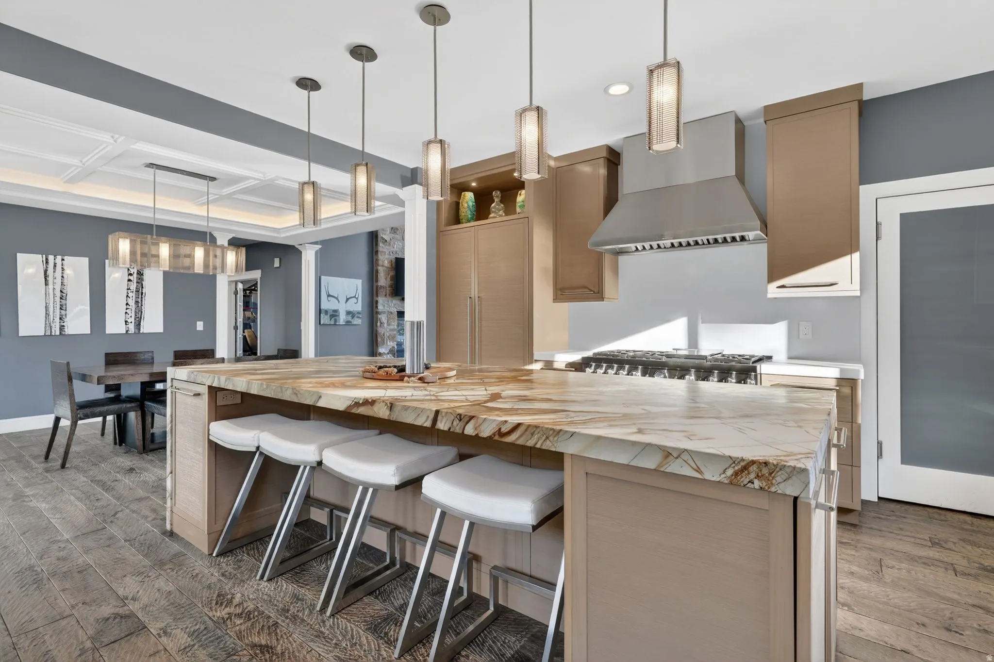 Kitchen featuring light wood finish cabinets, hanging light fixtures, dark wood-type flooring, a breakfast bar area, and coffered ceiling