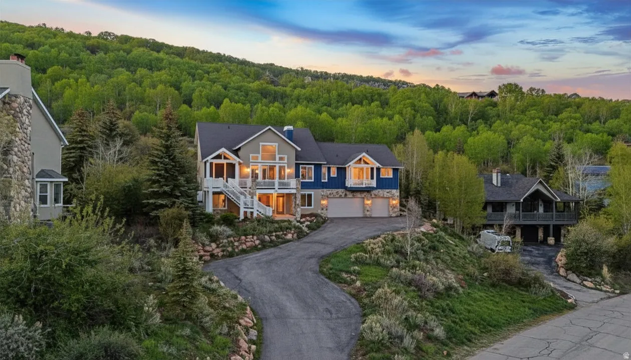 View of front of home with a chimney, asphalt driveway, an attached garage, and a balcony