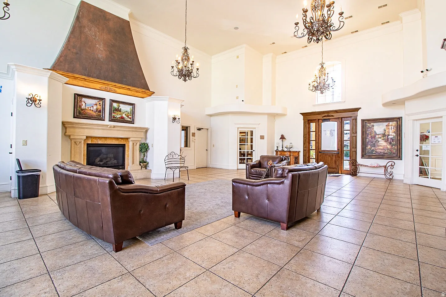 Living room featuring a high ceiling, a fireplace, ornamental molding, suspended lighting, and light tile patterned flooring