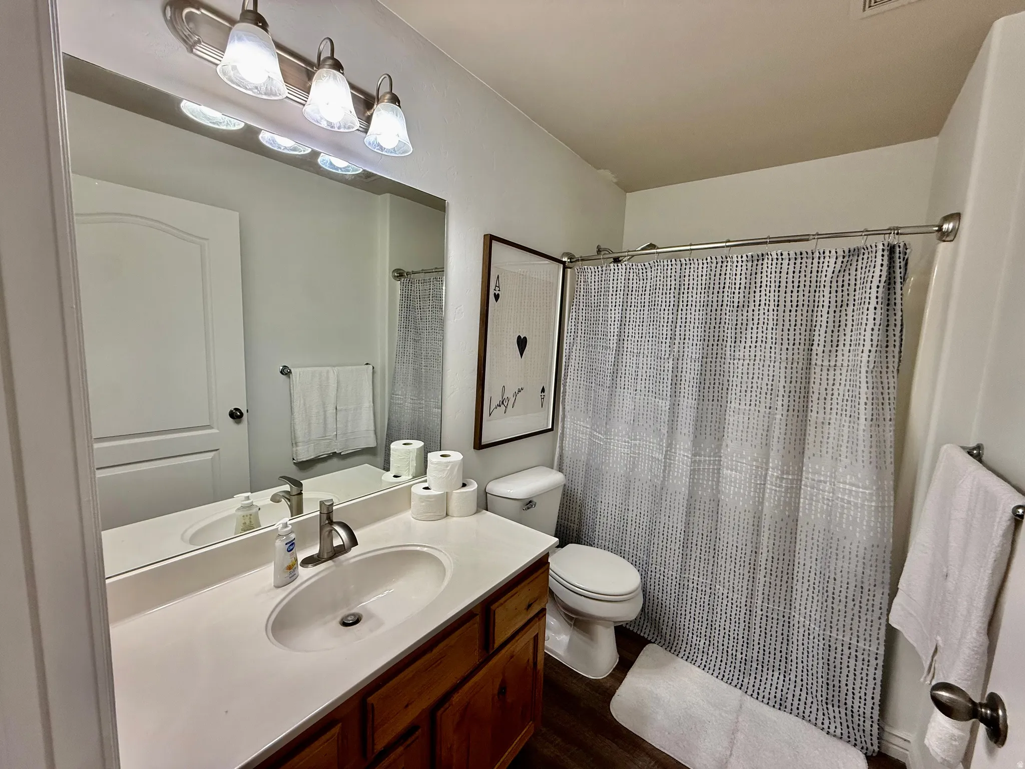 Bathroom with vanity, a shower with shower curtain, and dark wood-style floors