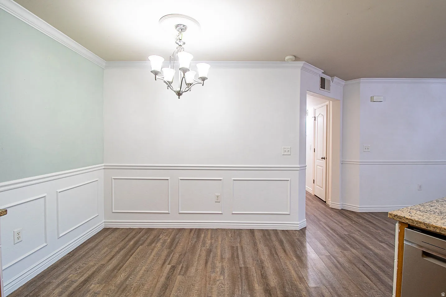 Unfurnished dining area featuring ornamental molding, suspended lighting, and dark wood-style floors