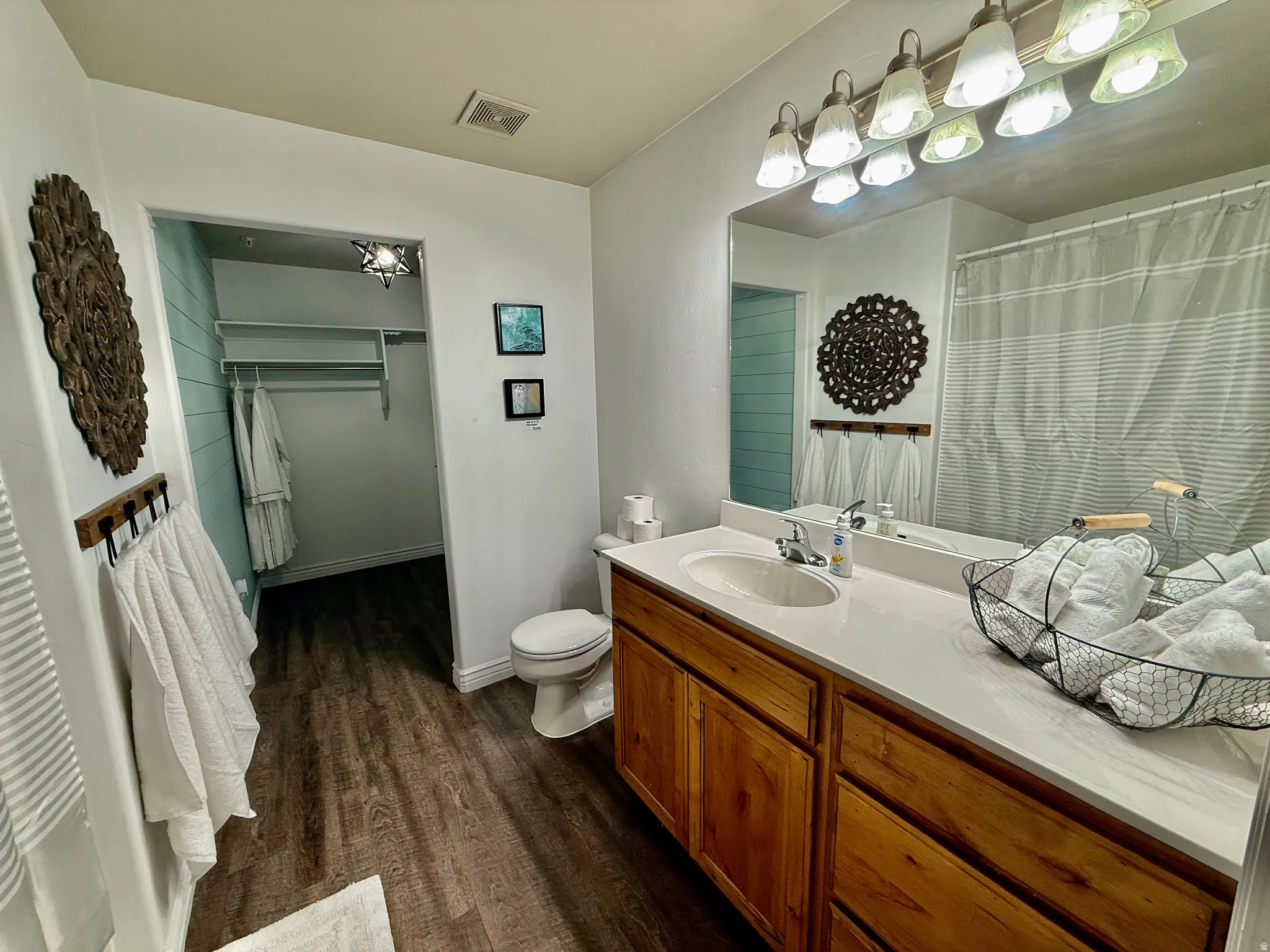 Full bathroom featuring a spacious closet, vanity, dark wood-style flooring, and curtained shower
