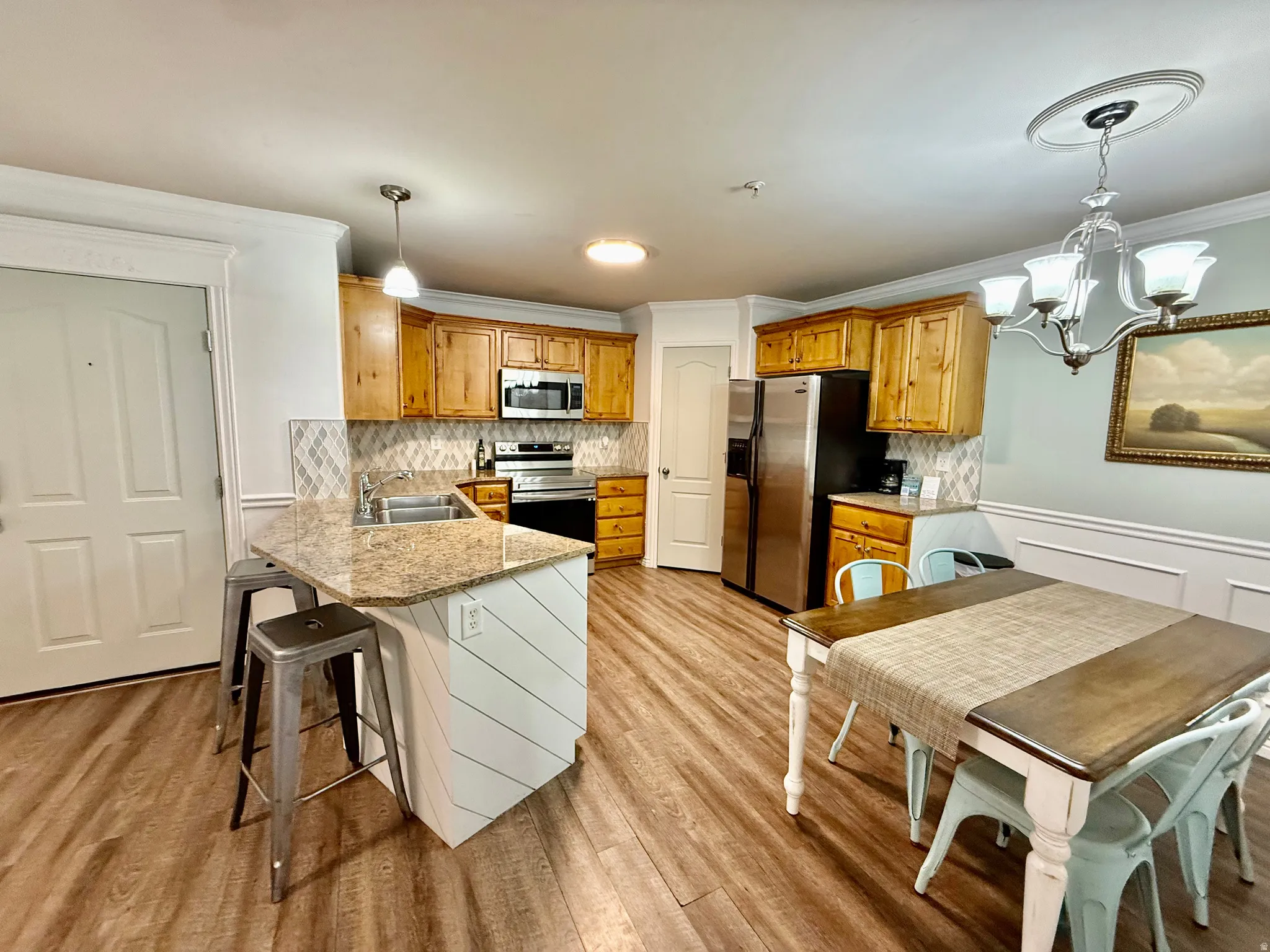 Kitchen featuring a breakfast bar, a peninsula, crown molding, a chandelier, and stainless steel appliances
