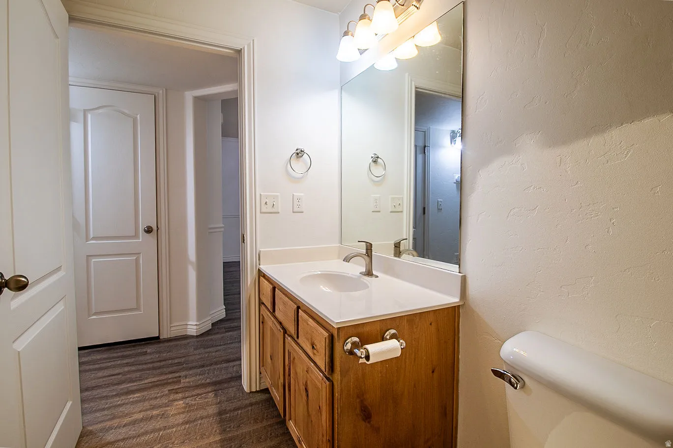 Half bath featuring vanity, dark wood-style flooring, and a textured wall
