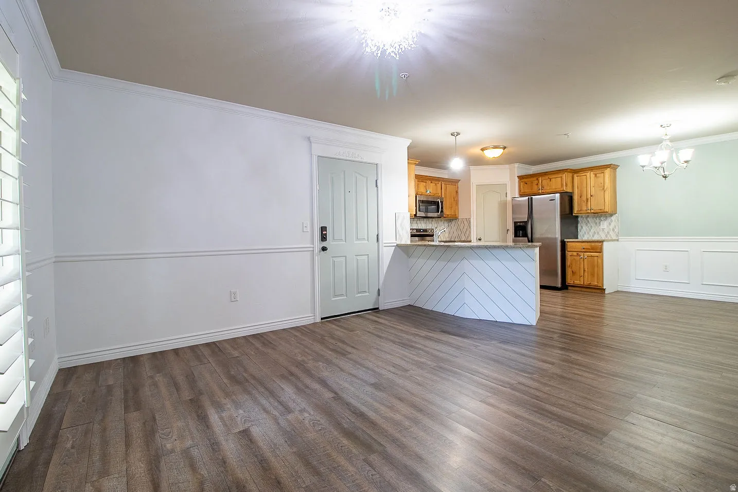 Kitchen featuring ornamental molding, a peninsula, a chandelier, light countertops, and stainless steel appliances
