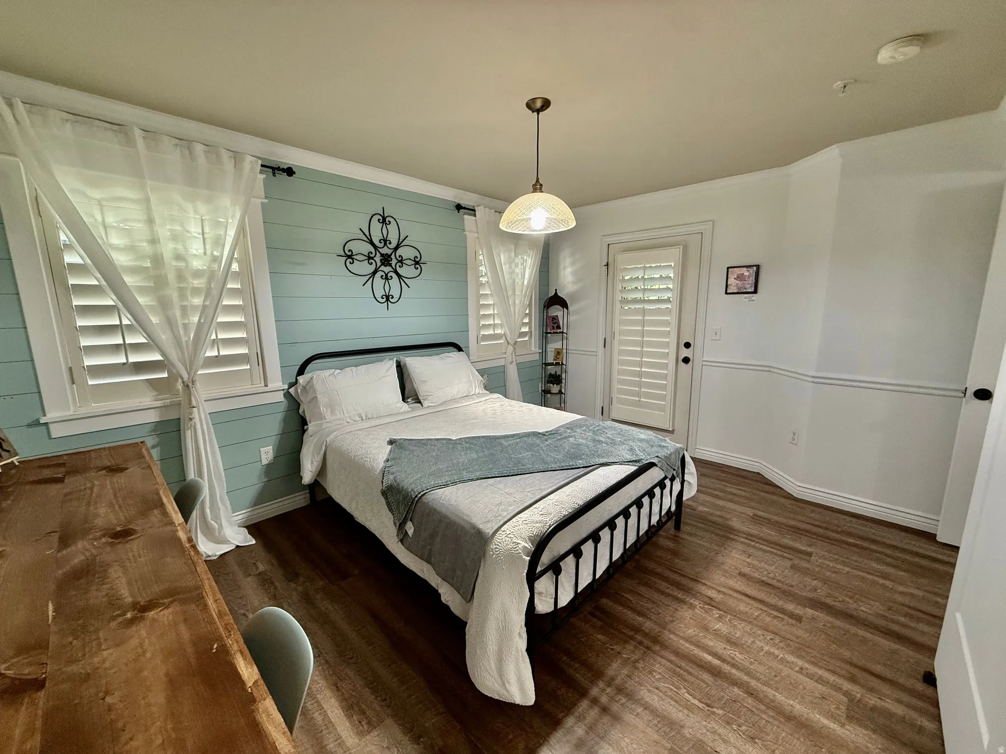 Bedroom featuring dark wood-style flooring, crown molding, and wooden walls