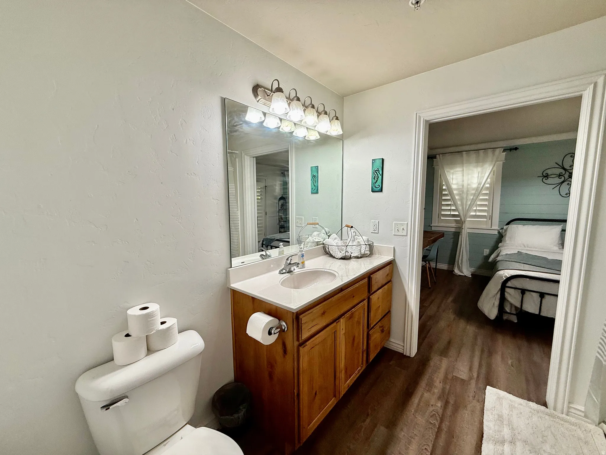 Ensuite bathroom with vanity, dark wood-style floors, and a textured wall