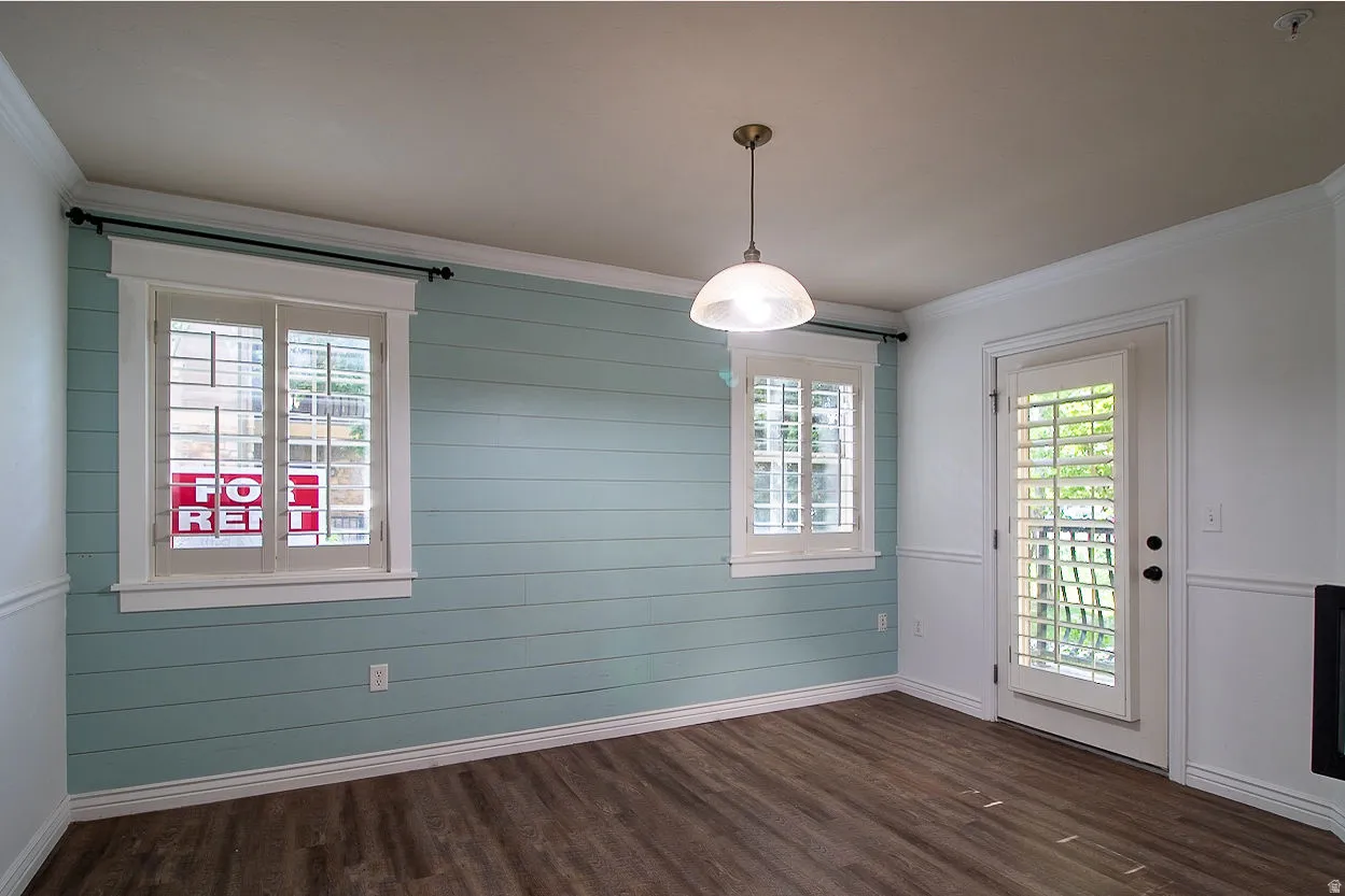 Unfurnished dining area with crown molding and dark wood-style floors