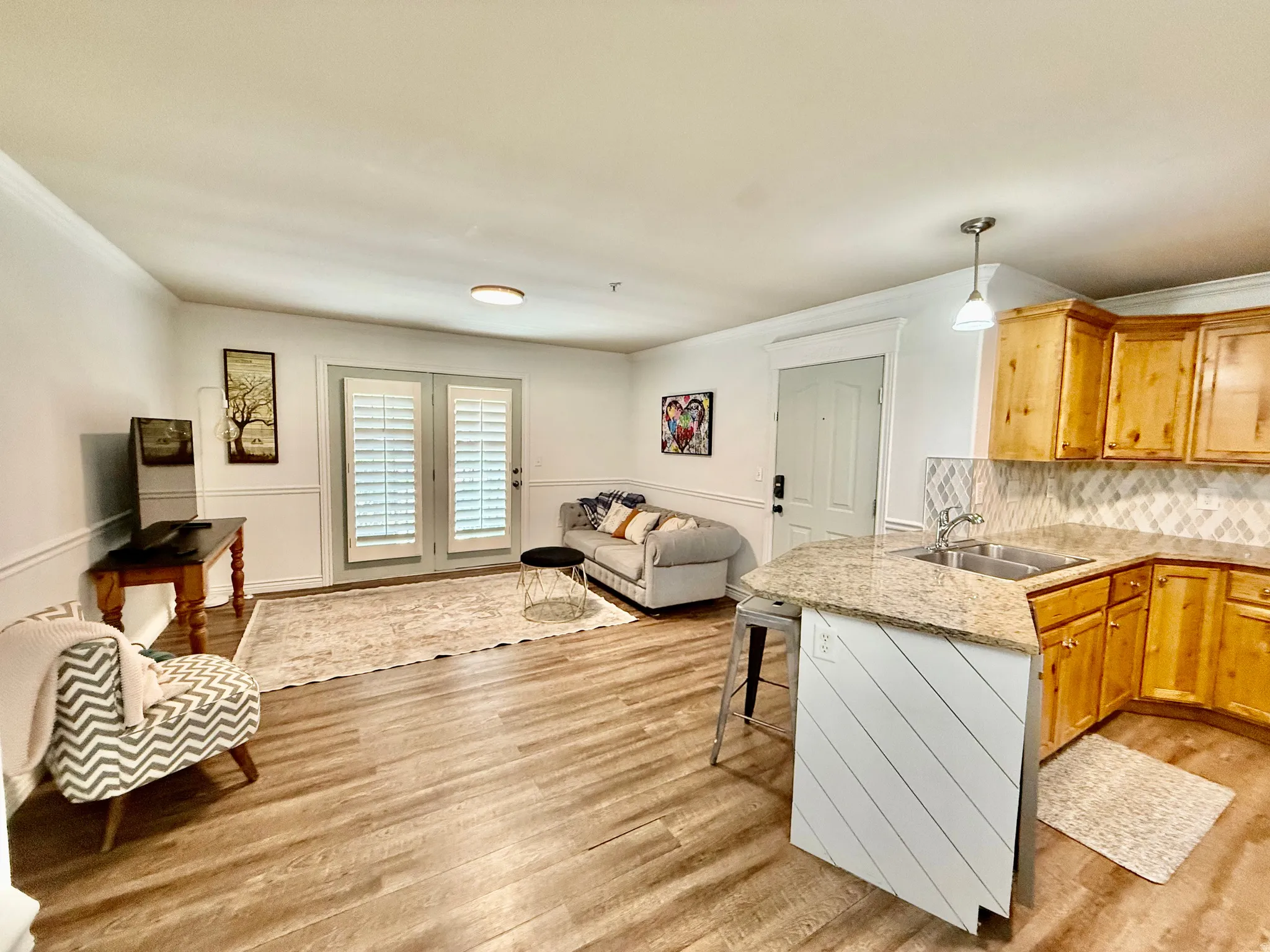 Kitchen with open floor plan, a peninsula, a kitchen breakfast bar, pendant lighting, and light wood-style floors