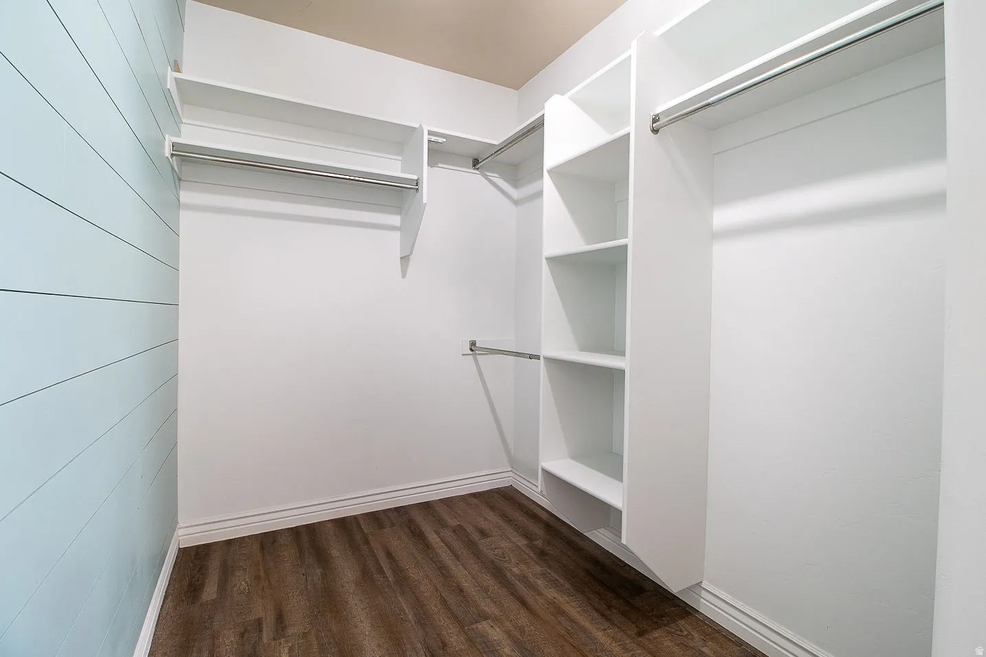 Walk in closet with dark wood-style flooring
