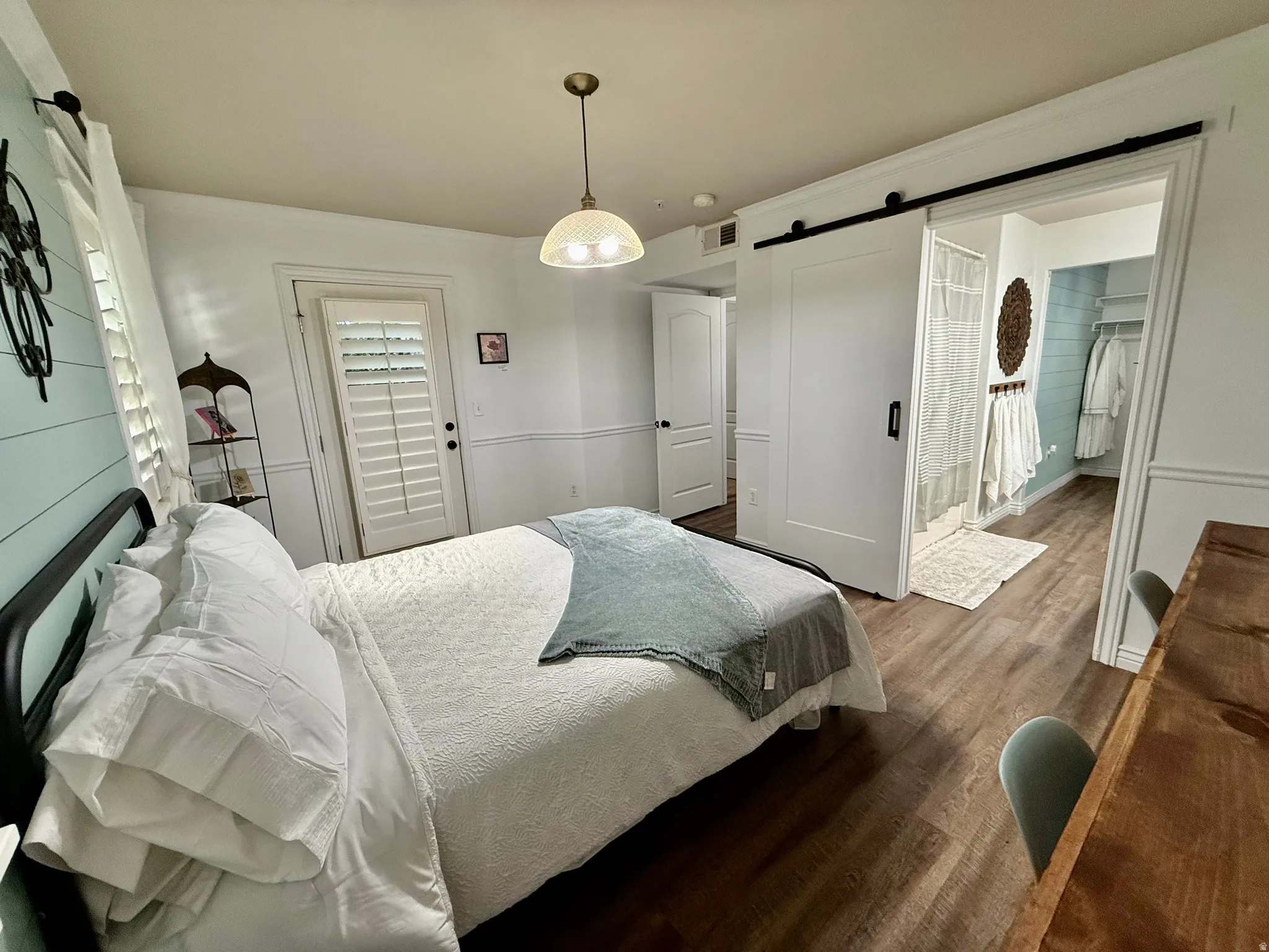 Bedroom featuring a barn door, dark wood finished floors, and connected bathroom