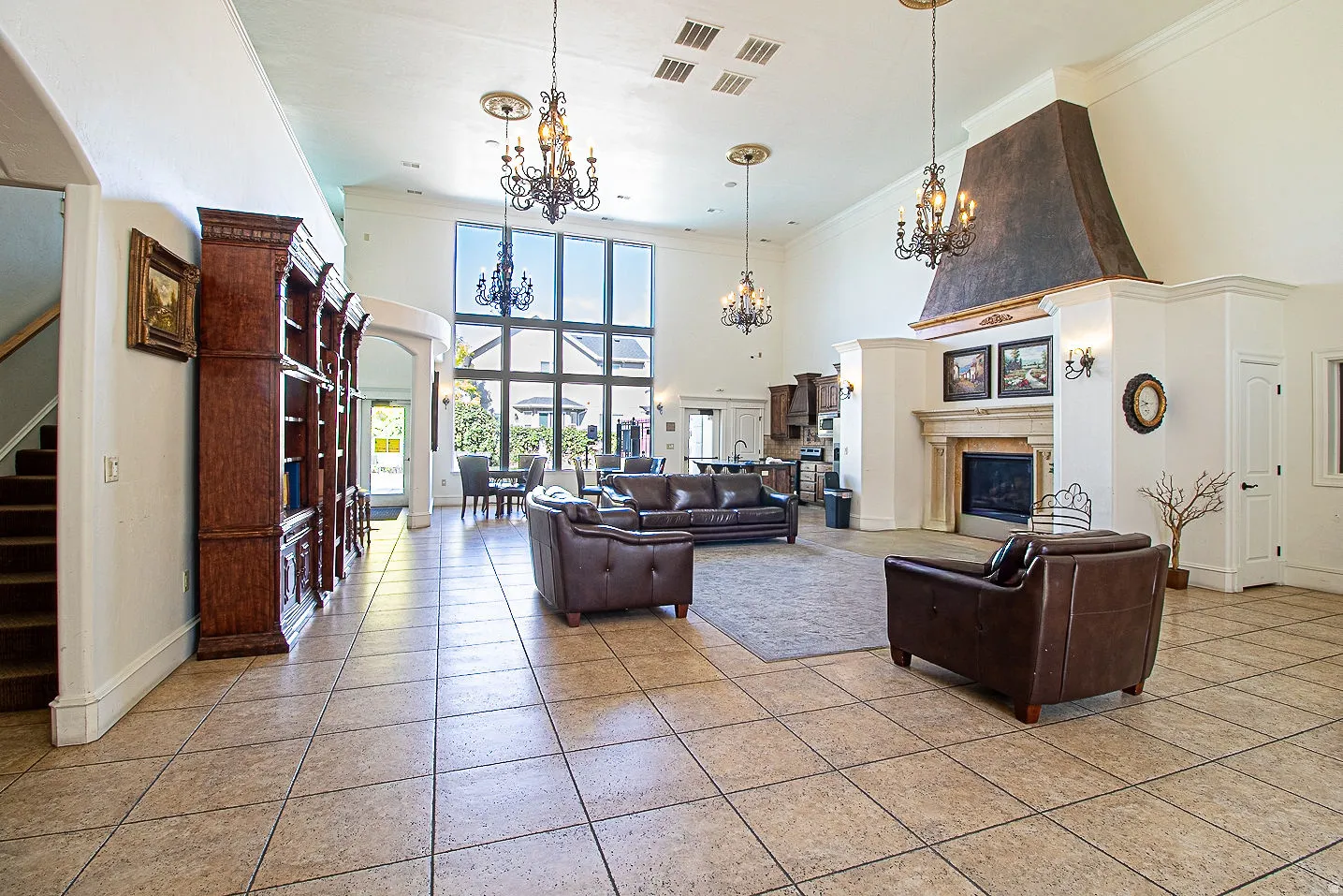 Living room with crown molding, a high ceiling, a glass covered fireplace, light tile patterned floors, and arched walkways
