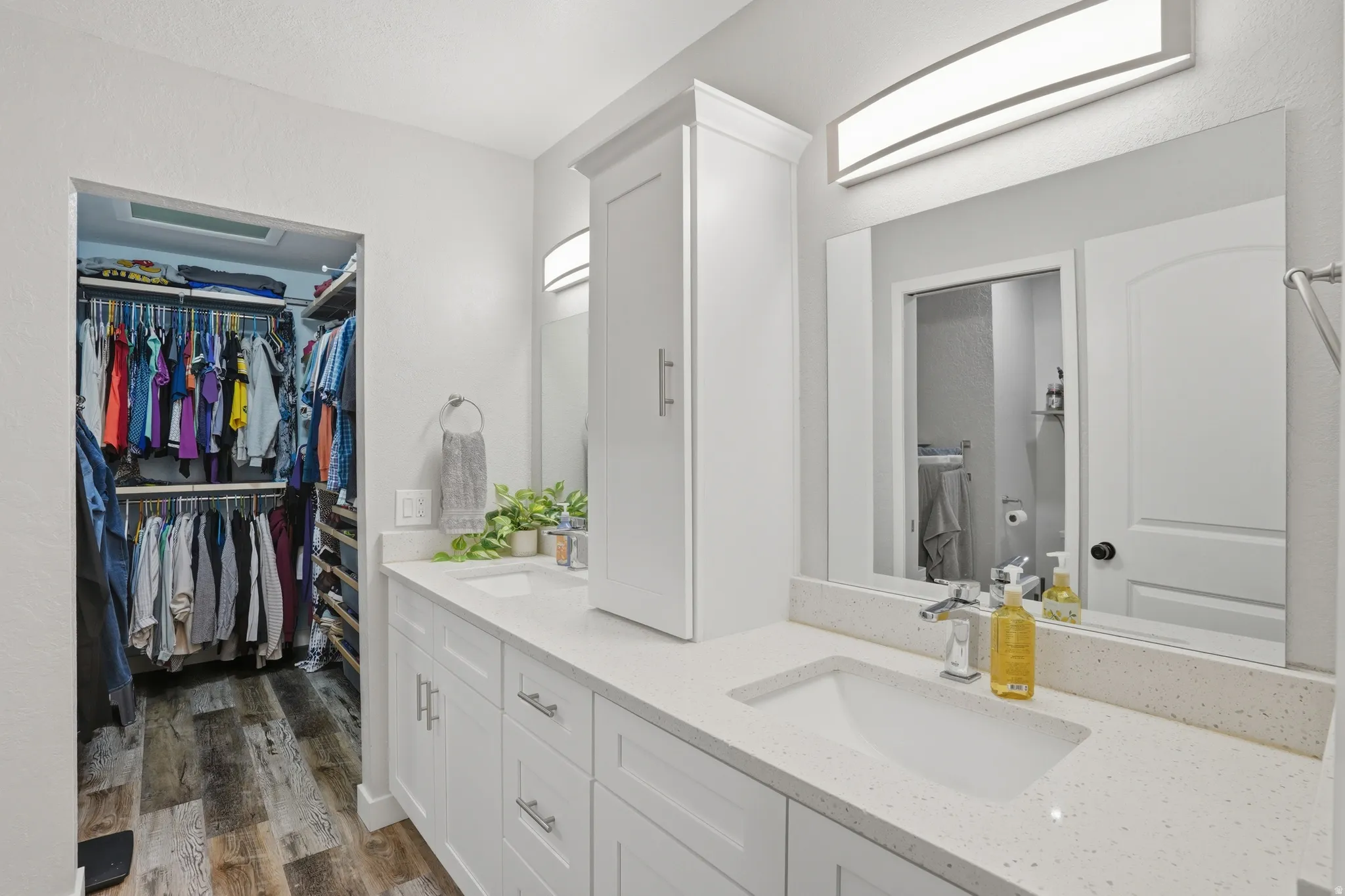 Full bathroom featuring double vanity, dark wood-style floors, and a walk in closet