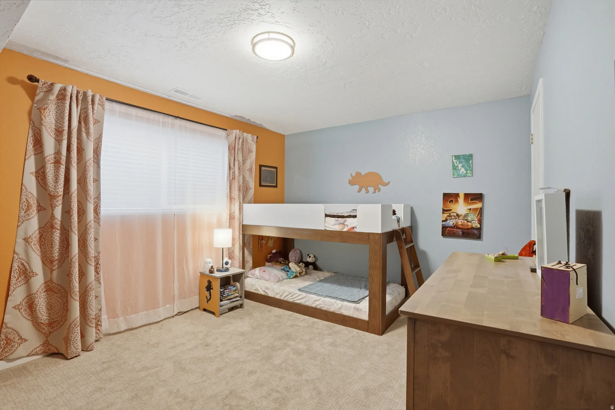 Bedroom with light colored carpet and a textured ceiling