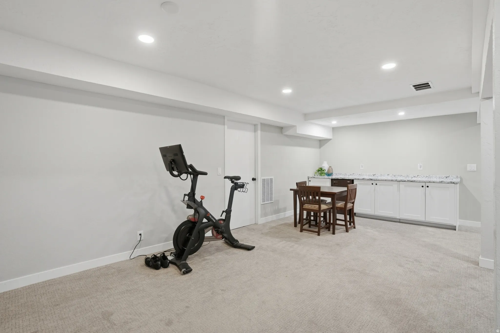 Exercise area with light carpet, recessed lighting, and wet bar