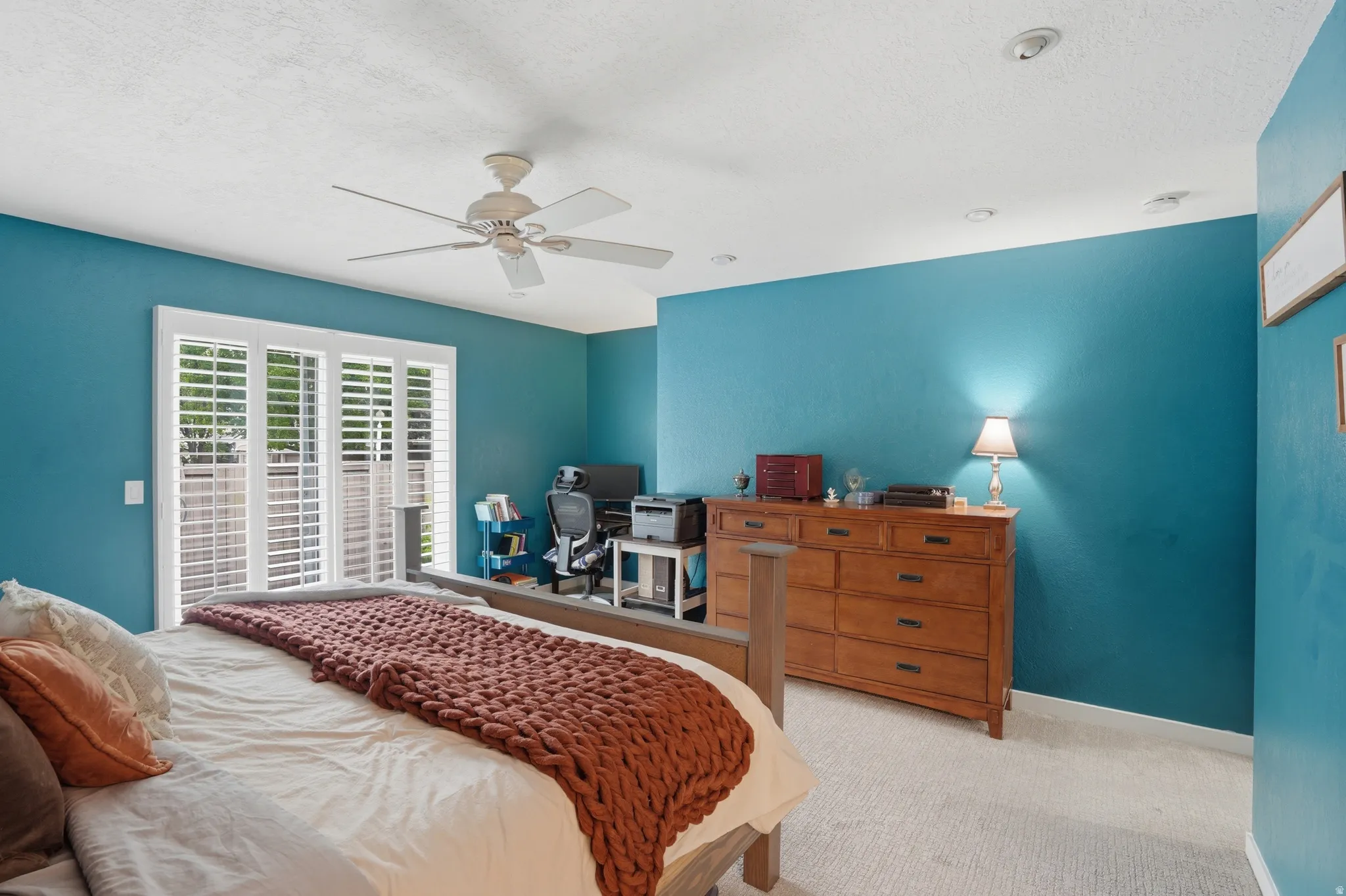 Bedroom featuring light carpet, a ceiling fan, and a textured ceiling