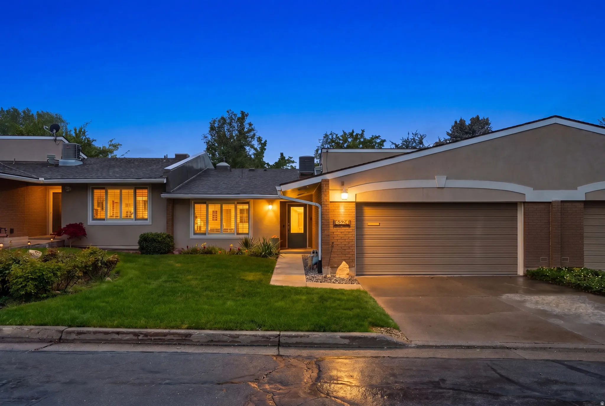 View of front facade featuring brick siding, an attached garage, concrete driveway, a front yard, and stucco siding