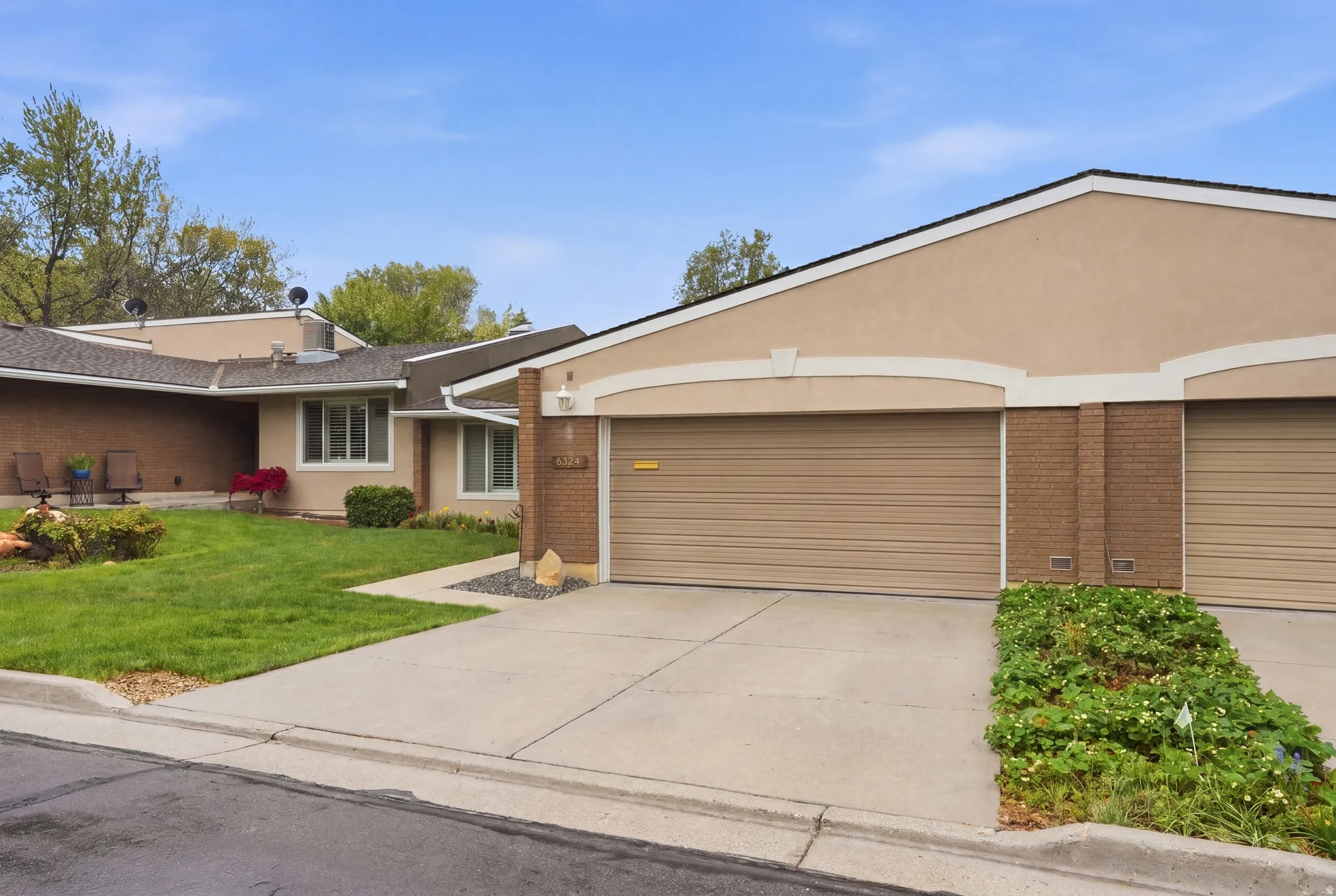 View of front facade with driveway, stucco siding, an attached garage, and brick siding