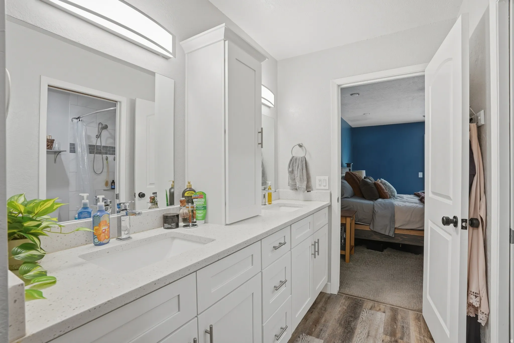 Bathroom with double vanity, connected bathroom, curtained shower, and dark wood-style floors