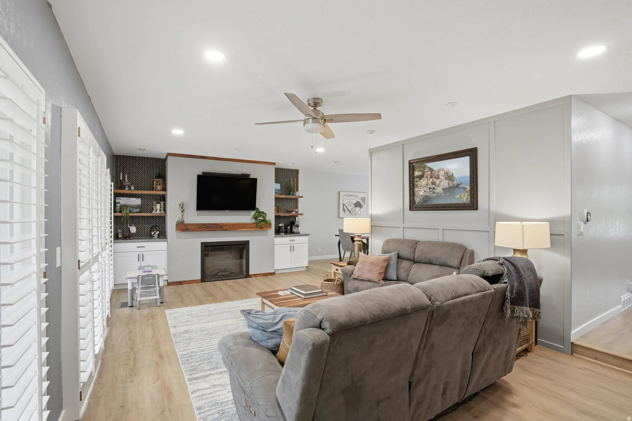 Living area featuring a ceiling fan, light wood-type flooring, recessed lighting, and a glass covered fireplace