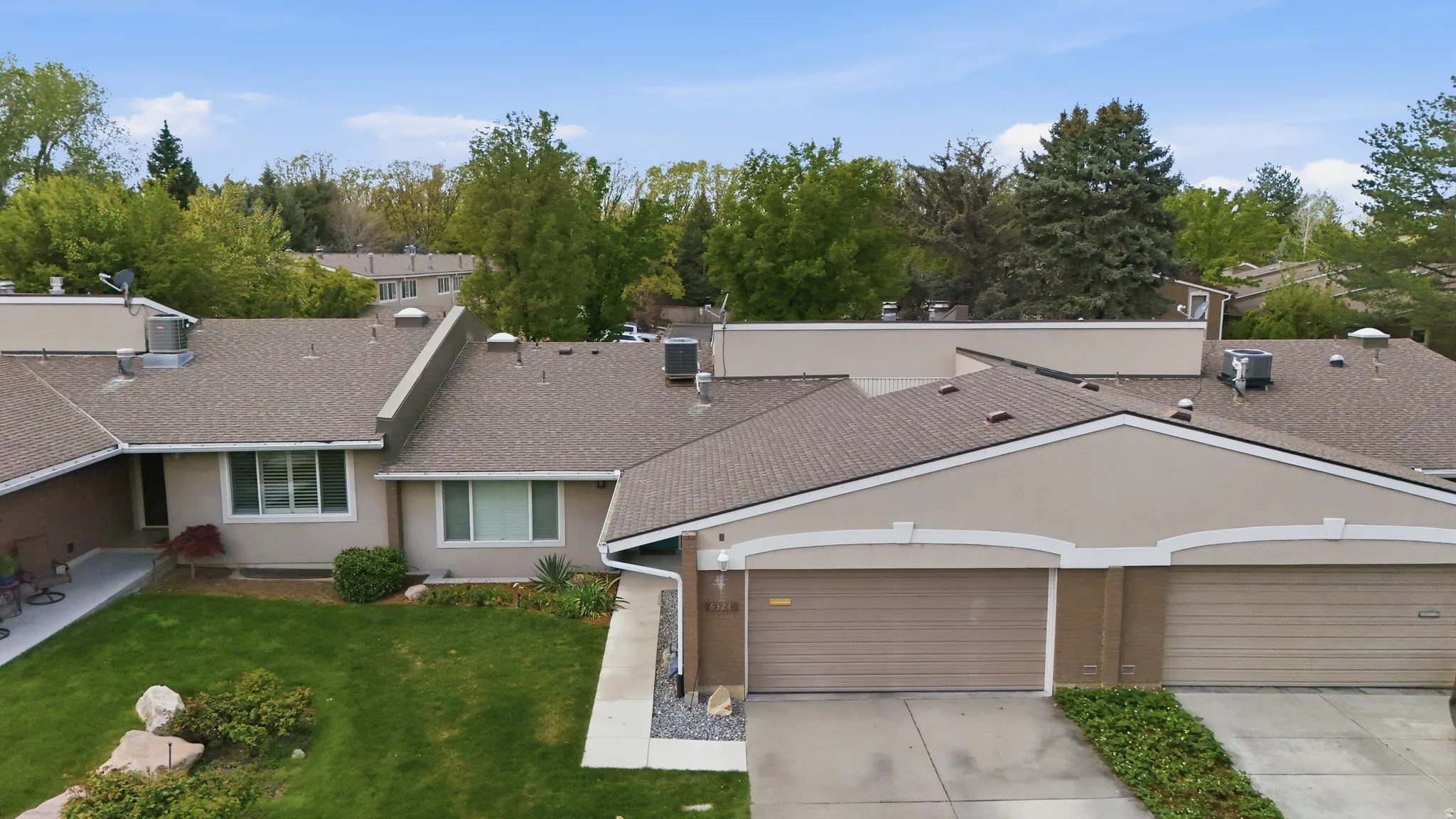 View of front of property featuring concrete driveway, an attached garage, a front yard, a shingled roof, and stucco siding