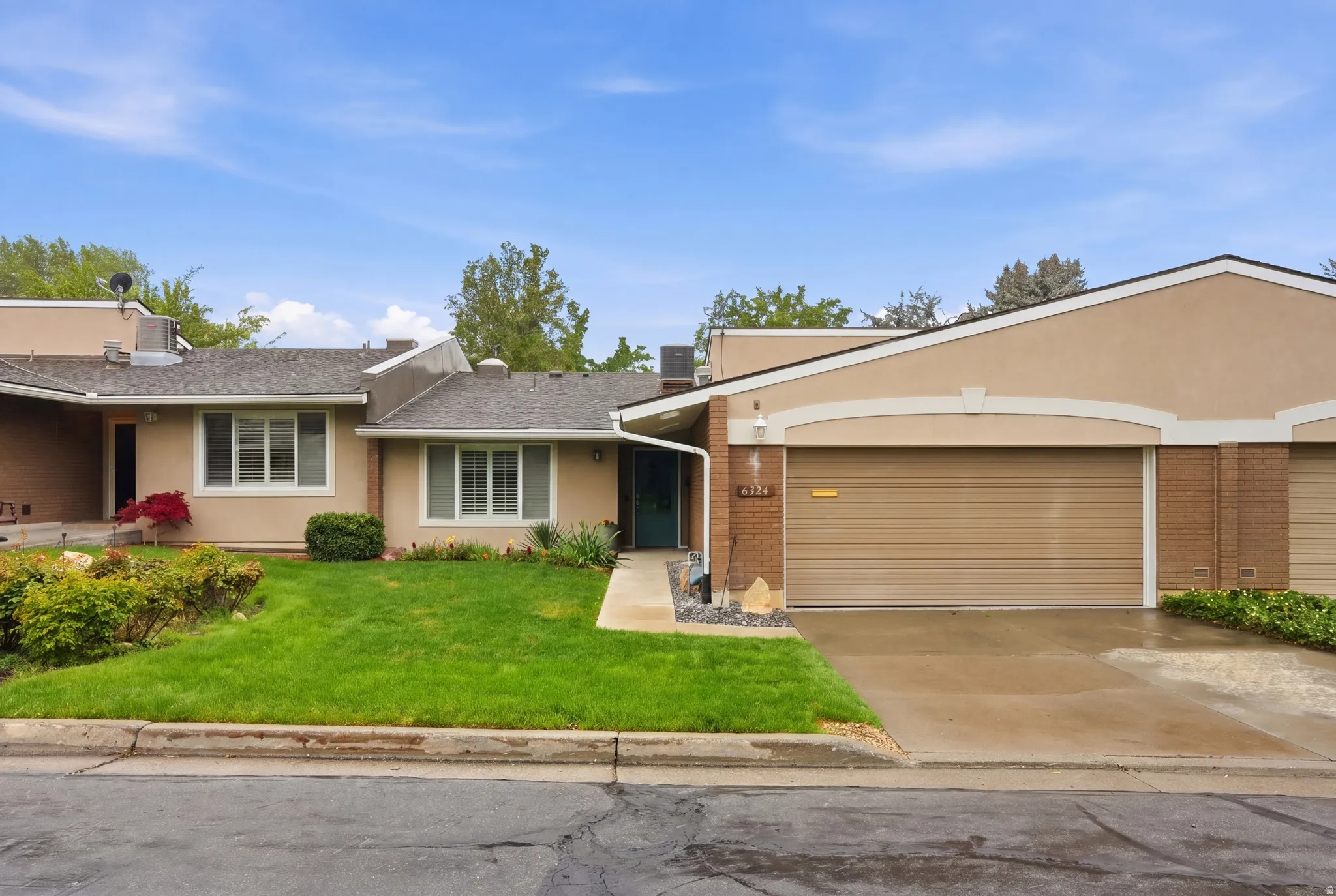 View of front of home featuring brick siding, a front lawn, concrete driveway, an attached garage, and stucco siding