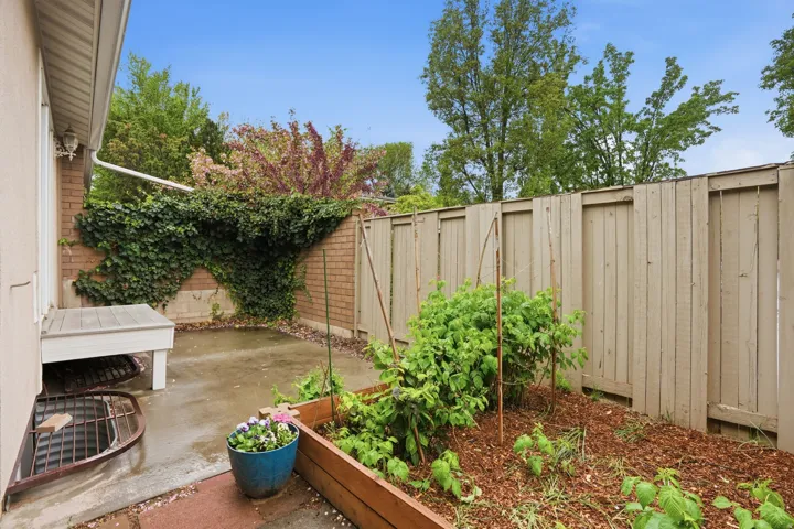 Fenced backyard featuring a patio and a vegetable garden