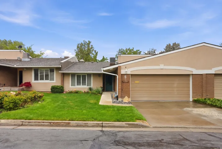 View of front of home featuring brick siding, a front lawn, concrete driveway, an attached garage, and stucco siding