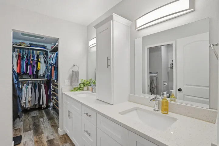 Full bathroom featuring double vanity, dark wood-style floors, and a walk in closet