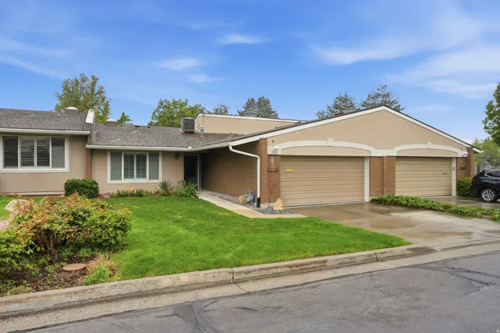 Ranch-style house with brick siding, a front lawn, an attached garage, concrete driveway, and stucco siding