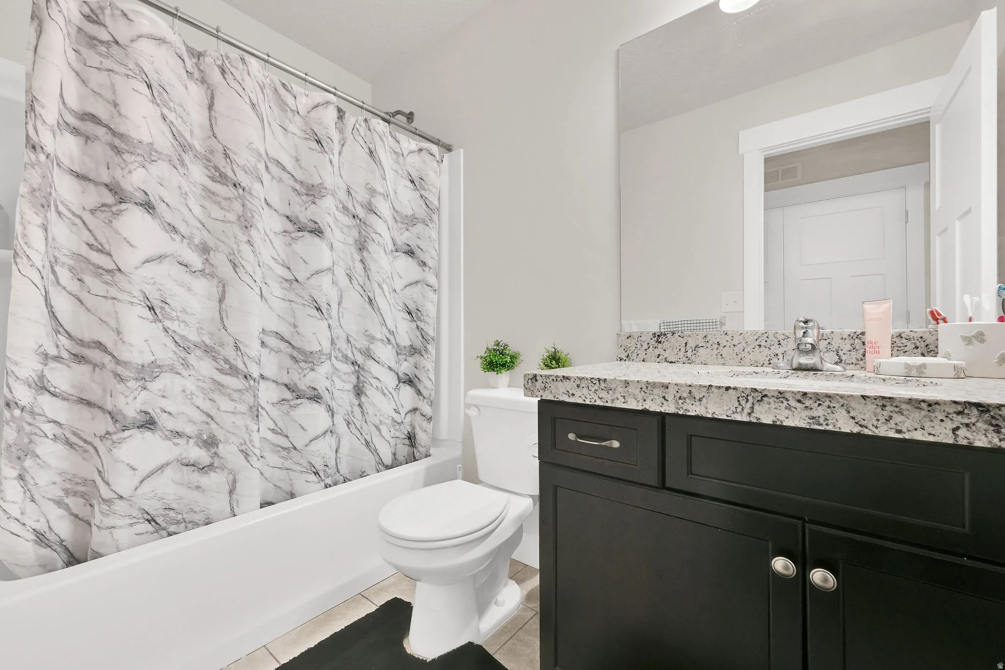 Full bath with vanity, shower / tub combo with curtain, and light tile patterned flooring