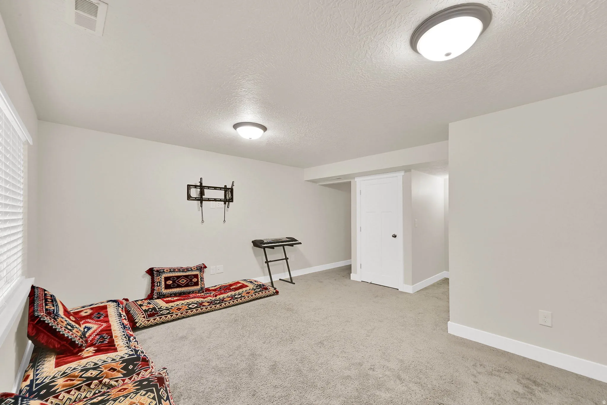 Living area featuring light carpet and a textured ceiling