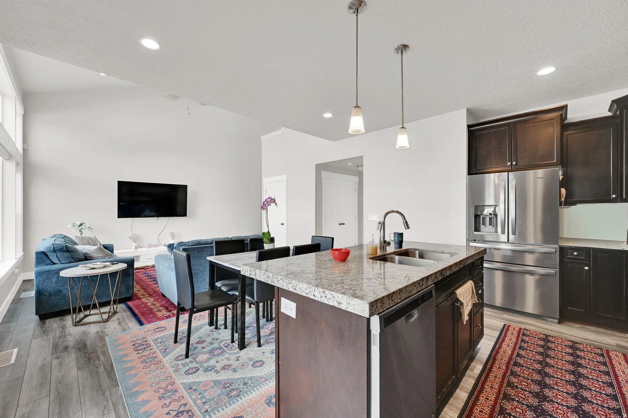 Kitchen featuring stainless steel appliances, open floor plan, an island with sink, dark wood finish cabinetry, and light wood-style floors